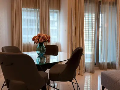 a table with chairs and a vase with flowers on it at ASHRI Luxury apt Steps to Dubai Mall & Burj Khalifa in Dubai