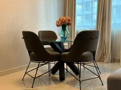 a dining room table with two chairs and a vase of flowers at ASHRI Luxury apt Steps to Dubai Mall & Burj Khalifa in Dubai