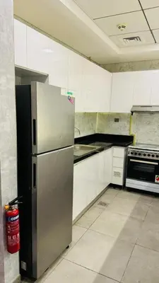 a kitchen with a stainless steel refrigerator and white cabinets at Modern Homestay Oval Tower, Business Bay in Dubai