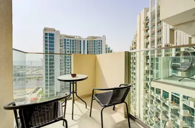 a balcony with two chairs and a table and some buildings at TRPS - Farhad Azizi, Al Jaddaf - Premium 1BR, Furnished with Pool View in Dubai