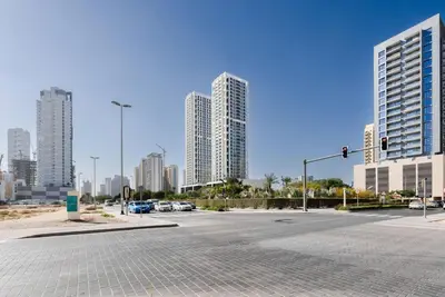 an empty street in a city with tall buildings at Fully Equipped Studio with Kitchen and Free Wi-Fi in Dubai