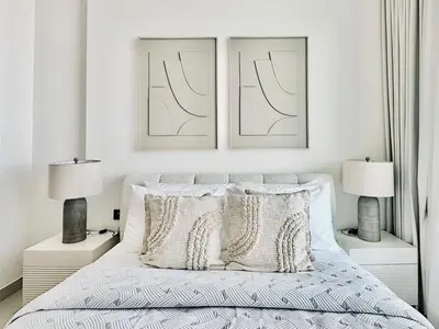 a white bedroom with two lamps and a bed at Cloud Level 1BR Calm with Parking Pool & Gym in Dubai