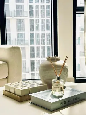 a table with a bottle of perfume and a book at Cream Toned 1BR Suite with Parking Pool & Gym in Dubai