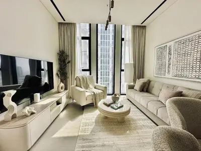 a living room with a couch and a tv at Cream Toned 1BR Suite with Parking Pool & Gym in Dubai