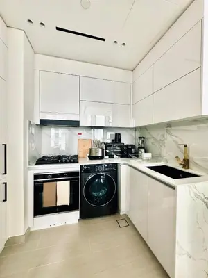a kitchen with white cabinets and a black dishwasher at Cream Toned 1BR Suite with Parking Pool & Gym in Dubai
