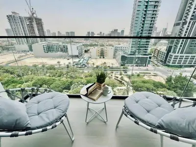 a balcony with two chairs and a table and a large window at Chic 1BR with free Pool & Gym - Near Mall of Emirates in Dubai