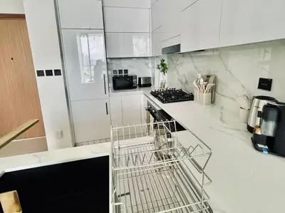 a white kitchen with a dish rack on a counter at Chic 1BR with free Pool & Gym - Near Mall of Emirates in Dubai