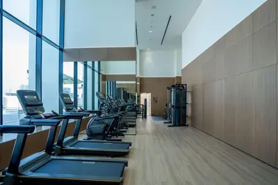 a row of treadmills in a gym with windows at Chic 1BR with free Pool & Gym - Near Mall of Emirates in Dubai