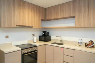 a kitchen with white counters and wooden cabinets at Live the Opulenco Experience! 2BR Urban Oasis by Missoni, Business Bay in Dubai