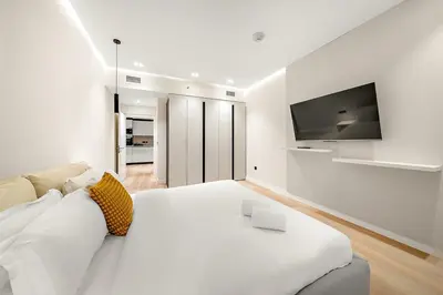 a white living room with a white couch and a tv at FIRST CLASS 1BR High Floor Luxury & Palm View in Dubai