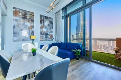 a dining room with a blue couch and a table and chairs at Private room in BURJ KHALIFA facing 3BR luxury apartment in Downtown Near Dubai Mall Metro in Dubai