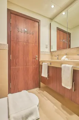 a bathroom with a wooden door and a sink at Private room in BURJ KHALIFA facing 3BR luxury apartment in Downtown Near Dubai Mall Metro in Dubai