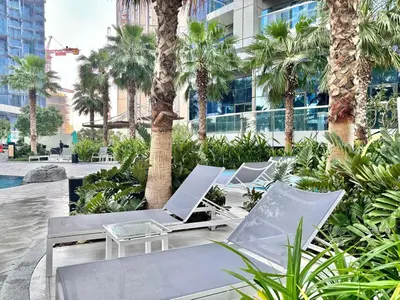 a row of chaise lounge chairs and palm trees at FIRST CLASS 2BR Mesmerizing Burj Khalifa View in Dubai