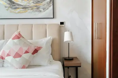 a bed with a pink and white pillow and a lamp at 2BR Downtown Gem with Burj Khalifa and Fountain Views in Dubai