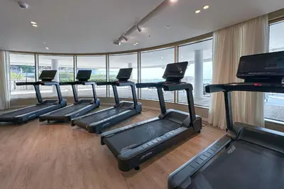 a gym with a row of treadles in a room with windows at Fantastic 2BR apartment Palm, Sea and Sunset Views in Dubai