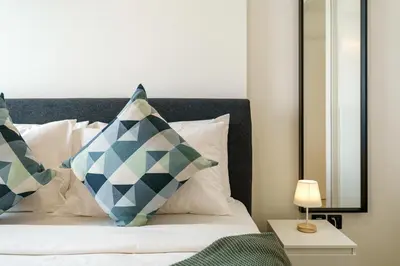 a bed with blue and white pillows and a mirror at 1BR Little Haven in Collective T1, Dubai Hills in Dubai