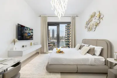 a white bedroom with a bed and a chandelier at Sparkle Tower by Swarovski, Full Marina View, 2min JBR & Metro, Sleeps 4 in Dubai