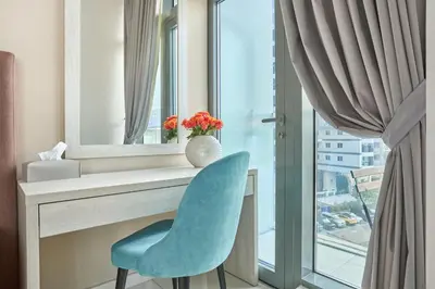 a desk with a blue chair in front of a window at Beachfront Bliss, Seven Palm Studio Apartment in Dubai