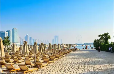 a row of chairs and umbrellas on a beach at Beachfront Bliss, Seven Palm Studio Apartment in Dubai