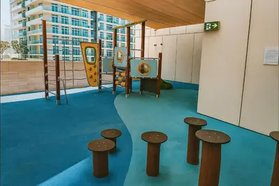a childrens play area with a playground with stools at Serene Ocean Views, 2BR Emaar Beachfront in Dubai