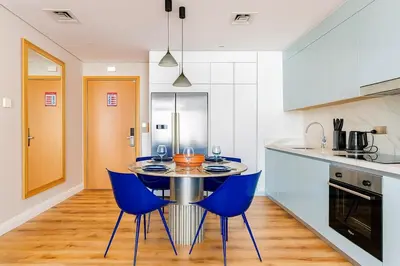 a kitchen with a table and two blue chairs at Serene Ocean Views, 2BR Emaar Beachfront in Dubai
