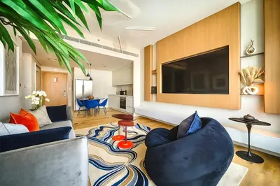 a living room with a blue couch and a large tv at Serene Ocean Views, 2BR Emaar Beachfront in Dubai