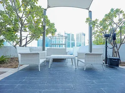 a group of white benches on a patio with trees at Luxury Studio | Near Dubai Mall | Lake View in Dubai