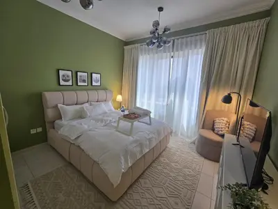 a bedroom with a large bed and a table at Modern Apt just Steps to Metro & Lake with Pool andParking in Dubai