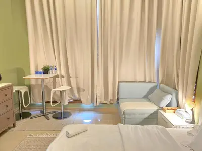 a bedroom with a bed and a chair and curtains at Charming Studio Near World Trade Center & Subway in Dubai