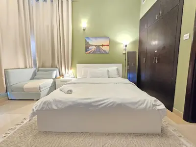 a bedroom with a large white bed and a chair at Charming Studio Near World Trade Center & Subway in Dubai