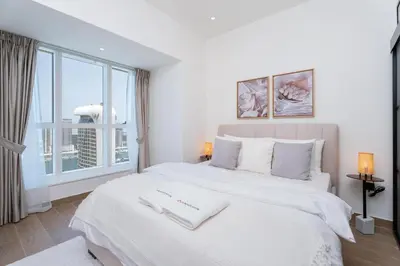 a bedroom with a large white bed with a window at Gala Guests - Elite Sea View Suites Dubai Marina in Dubai