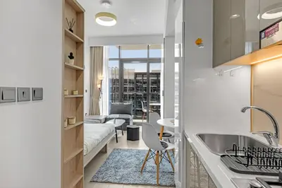 a kitchen with a sink and a living room at Waves - Stylish and Comfy Couples Retreat Apt with Balcony in Dubai