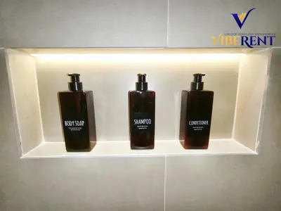 three shampoo bottles sitting on a shelf in a bathroom at 1BHK Pool Sauna 15 Min to Marina in Dubai