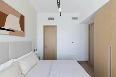 a bedroom with a bed and a painting on the wall at Modern 1-BR Apartment with Cozy Vibes Pool Gym in Dubai