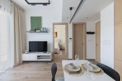 a living room with a table and a tv at Modern 1-BR Apartment with Cozy Vibes Pool Gym in Dubai