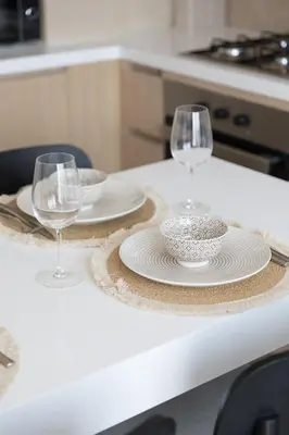 a table with two wine glasses and plates on it at Modern 1-BR Apartment with Cozy Vibes Pool Gym in Dubai