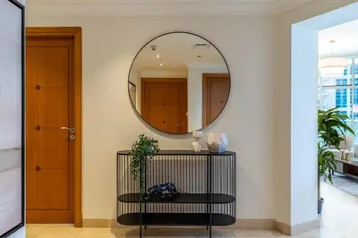 a hallway with a round mirror and a table at The Smart Concierge - Marinascape Avant in Dubai