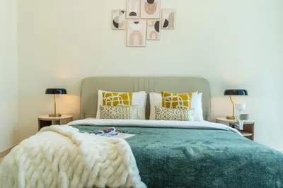 a bedroom with a bed with a green blanket and pillows at The Smart Concierge - Marinascape Avant in Dubai