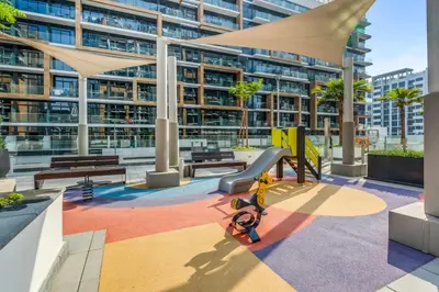 a playground in front of a large building at Stylish Apartment in Meydan in Dubai