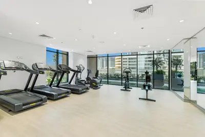 a gym with several treadmills and elliptical machines at Stylish Apartment in Meydan in Dubai
