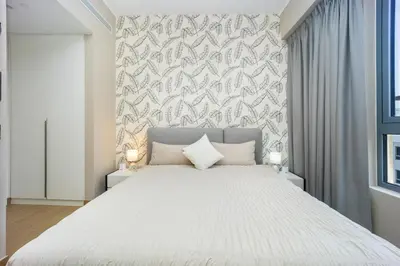 a bedroom with a white bed and a wall at Günstige Unterkunft mit Hafenblick in Port de La Mer in Dubai