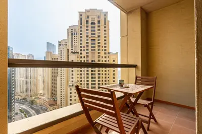 a table and chairs on a balcony with a view of a city at Chic 2-bed Oasis with Marina Views Walk to Beach! in Dubai