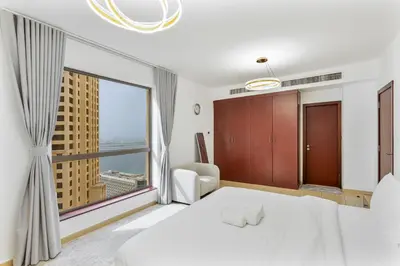 a bedroom with a white bed and a large window at Chic 2-bed Oasis with Marina Views Walk to Beach! in Dubai