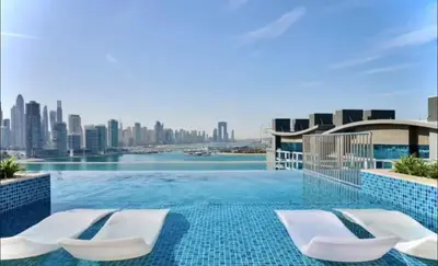 a swimming pool with two chairs and a city skyline at Beachfront Bliss Seven Palm in Dubai