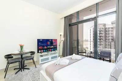 a bedroom with a bed and a tv and a table at PVH - Azizi Riviera - Lovely Studio near Downtown in Dubai