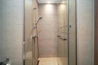 a shower with a glass door in a bathroom at PVH - Azizi Riviera - Lovely Studio near Downtown in Dubai