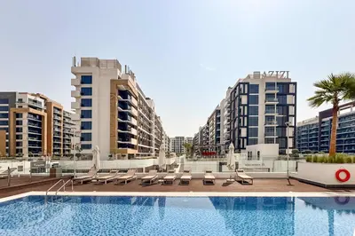 a swimming pool with lounge chairs and some buildings at PVH - Azizi Riviera - Lovely Studio near Downtown in Dubai