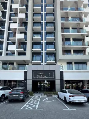 a parking lot with cars parked in front of a building at PVH - Azizi Riviera - Lovely Studio near Downtown in Dubai