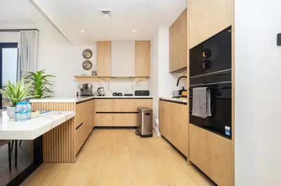 a kitchen with wooden cabinets and black appliances at Premium Apartment mit Strandzugang in Dubai in Dubai