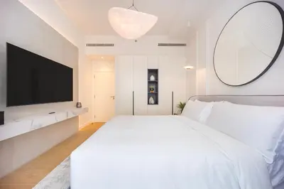 a white bedroom with a large bed and a flat screen tv at Premium Apartment mit Strandzugang in Dubai in Dubai